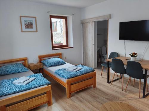 een kamer met 2 bedden, een tafel en een televisie bij Apartmán Opolany in Opolany