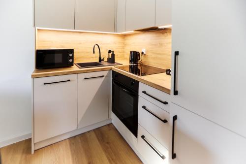 een keuken met witte kasten, een spoelbak en een magnetron bij Park & Town Apartment in Drawsko Pomorskie