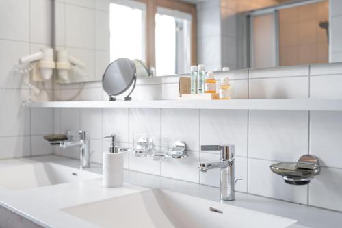 a white bathroom with a sink and a mirror at Haus Iris in Lech am Arlberg