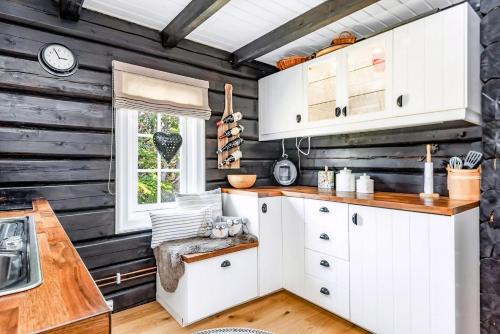eine Küche mit weißen Schränken und einer Holzwand in der Unterkunft Family-Friendly Log Cabin With Panoramic View in Østby