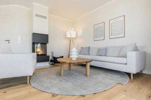 a living room with a couch and a table and a fireplace at De Bööi - Luxus-Haus mit Meerblick, Sauna & Kamin in Fehmarn