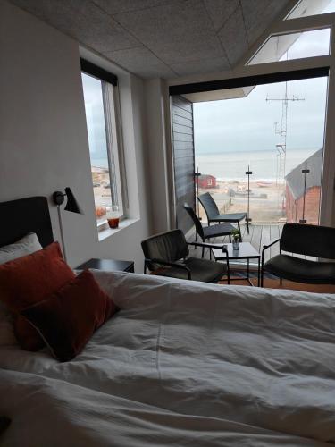 a bedroom with a bed and a balcony with chairs at Hotel og Restaurant Havbadet in Thisted