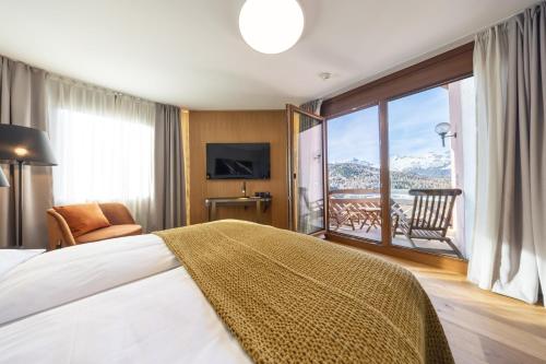 a bedroom with a bed and a view of a balcony at Hotel Rosatsch in Pontresina