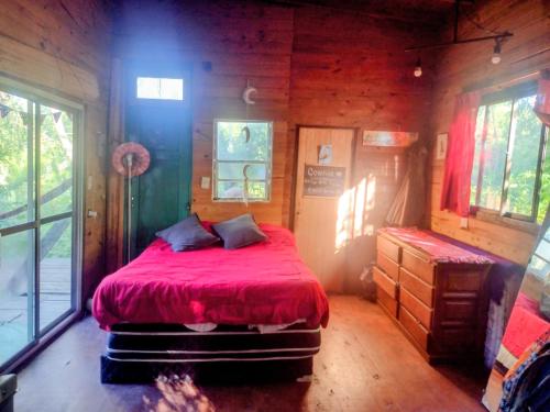 a bedroom with a red bed in a wooden cabin at Casita isleña in Tigre