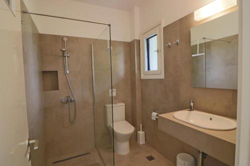 ein Badezimmer mit Dusche, Toilette und Waschbecken in der Unterkunft Eressos Ilios Apartments in Skala Eresou