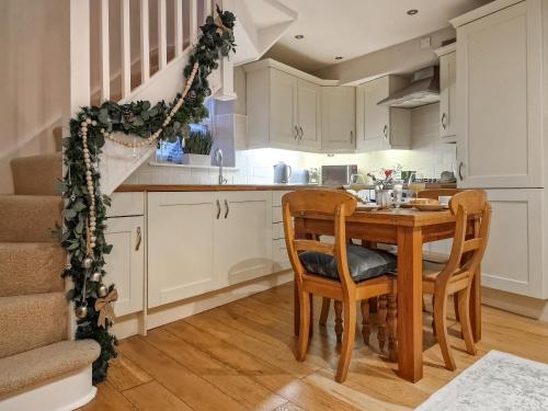 een keuken met een houten tafel en stoelen bij Thimble Cottage in St Bees