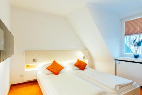 een wit bed met oranje kussens in een kamer bij Hotel Heideblick an der Lüneburger Heide in Jesteburg