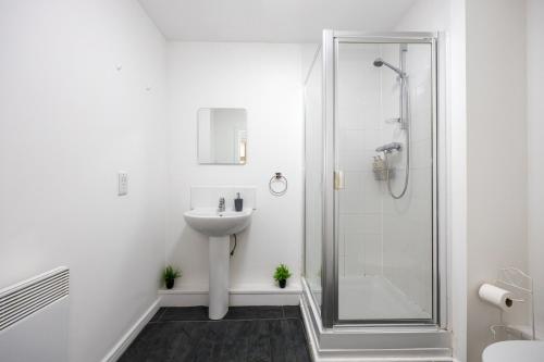 a white bathroom with a sink and a shower at Cityside Apartment Walk to Etihad & Coop Live in Manchester