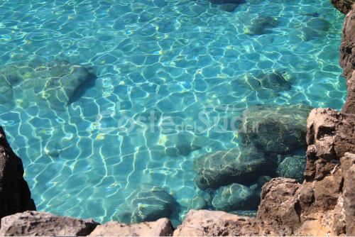 a pool of clear blue water with rocks in it at Residence Salento Fronte Mare in Torre San Giovanni Ugento