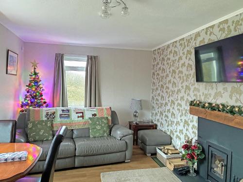 a living room with a couch and a christmas tree at Lilybank Cottage in Doularg
