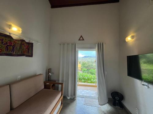 a room with a couch and a television and a window at Vila dos Cristais - Apartamentos de Temporada in Alto Paraíso de Goiás