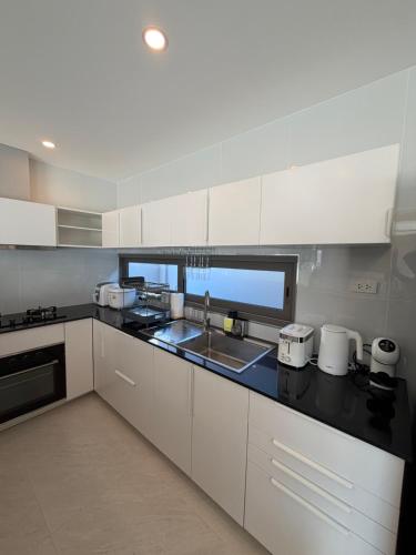een keuken met witte kasten en een zwart aanrechtblad bij CH Villa Sand Stone in Ko Samui