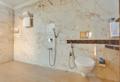a bathroom with a toilet and a shower at SaffronStays Green Lawns in Pāli