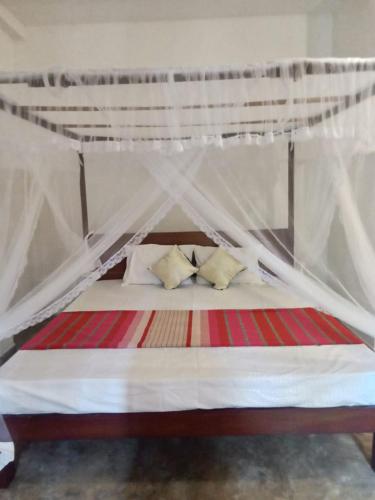 a bed with a canopy with two pillows on it at White Horizon 2 in Ahangama