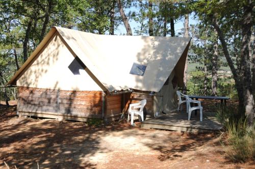 una yurta nel bosco con due sedie e un tavolo di Camping la Grangeonne a Esparron-de-Verdon