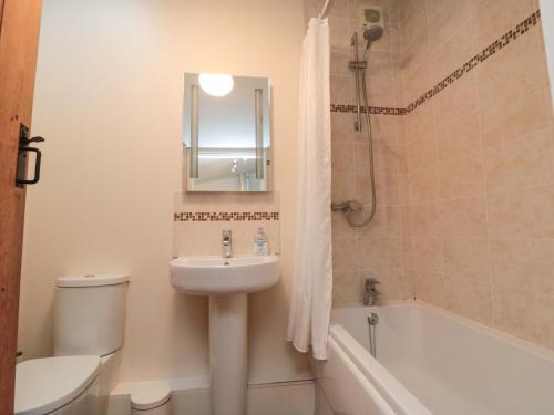 a bathroom with a sink and a toilet and a tub at Beacon Cottage in Pickering