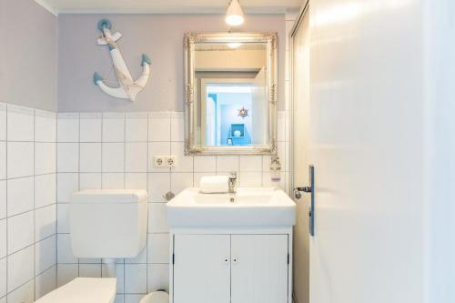 un bagno con lavandino, WC e specchio di Schipp Landen Lisa a Schobüll