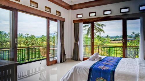 a bedroom with a bed and large windows at The Uma Tapan in Penginyahan