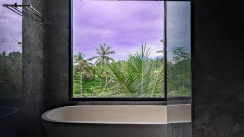 a bathroom with a window and a bath tub at The Uma Tapan in Penginyahan