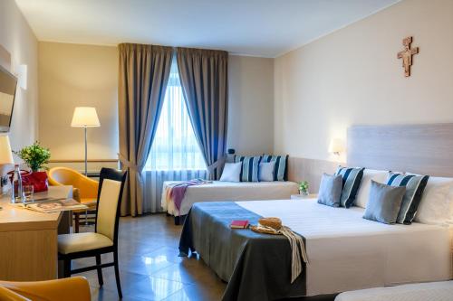 a hotel room with two beds and a desk at Domus Pacis Assisi in Assisi
