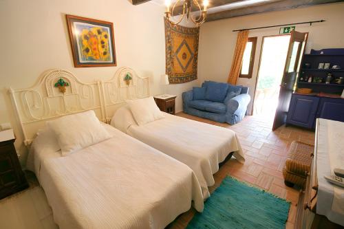 una camera con due letti e una sedia blu di Quinta das Achadas - Quartos a Cerro Ruivo