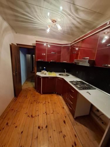 kuchnia z czerwonymi szafkami i drewnianą podłogą w obiekcie Deniz Hotel w mieście Gandża