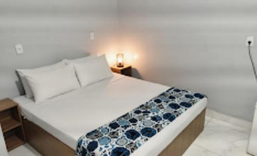 una camera da letto con un letto bianco con fiori blu di Hotel Gold - samambaia sul a Brasilia