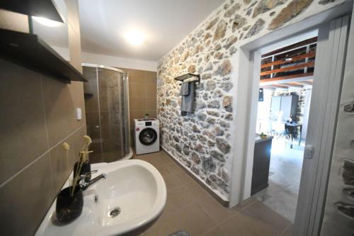 een badkamer met een wastafel en een stenen muur bij Markos House in Kalymnos