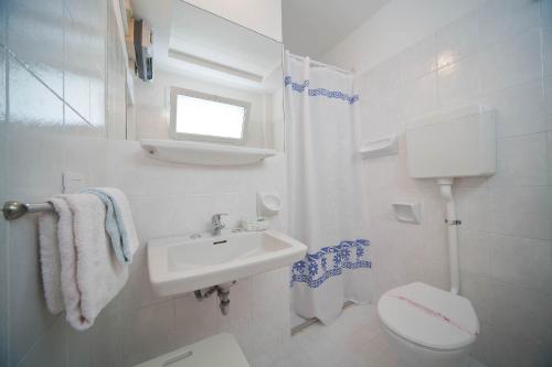a white bathroom with a toilet and a sink at Hotel Derby in Riccione
