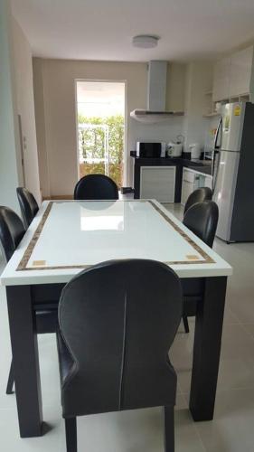 a kitchen with a table with chairs and a kitchen with a refrigerator at Shalom Casa Seaside Rayong in Ban Chak Phai