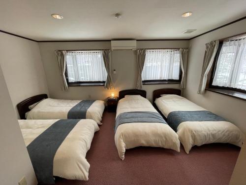 un gruppo di 4 posti letto in una camera con finestre di ペンション歩野慕野-honobono a Kitashiobara