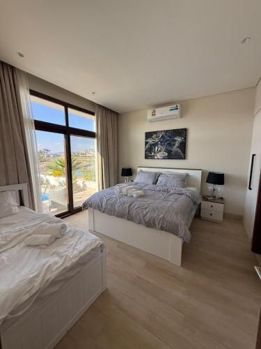 a bedroom with two beds and a large window at Villa Laguna Lux TU10 in Salalah