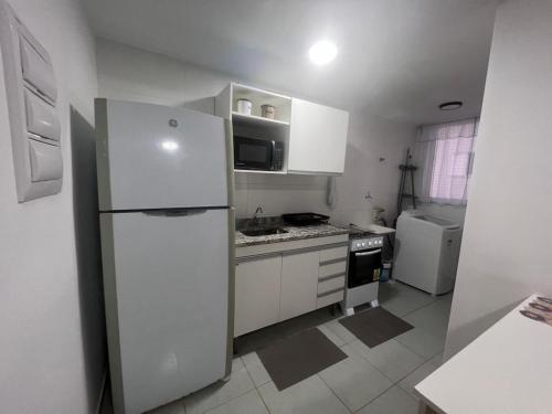 una cucina bianca con frigorifero e piano cottura di Apartamento proximo centro a Poços de Caldas