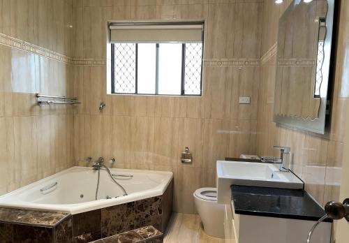 a bathroom with a tub and a toilet and a sink at Burwood central home in Sydney