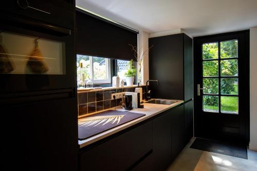 a kitchen with black cabinets and a sink and a window at Forest Inn in Ugchelen