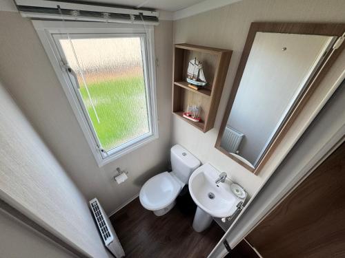 a bathroom with a toilet and a sink and a window at The Pilot s Rest sleeps 6 in Exmouth