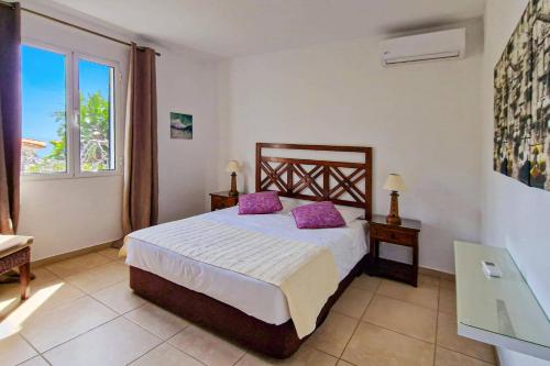 a bedroom with a bed with purple pillows and a window at Villa Casa Amelia Dio by Villa Plus in Caniço