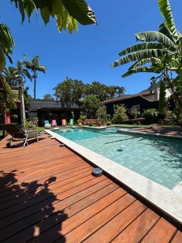 una piscina con terrazza in legno accanto a una casa di Pousada Preamare a Ubatuba
