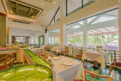 a restaurant with tables and chairs and large windows at Krabi Maritime Resort in Krabi
