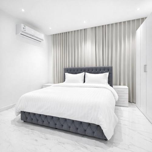 a white bedroom with a large bed with white sheets at Najd Cozy Apartment in Dammam