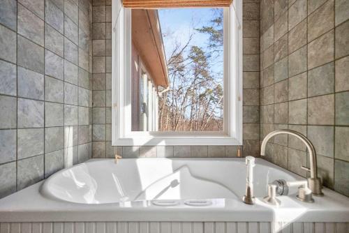 een badkuip in een badkamer met een raam bij 3 Fireplaces Hot Tub Fire Pit Deck Pool Access in Hedgesville