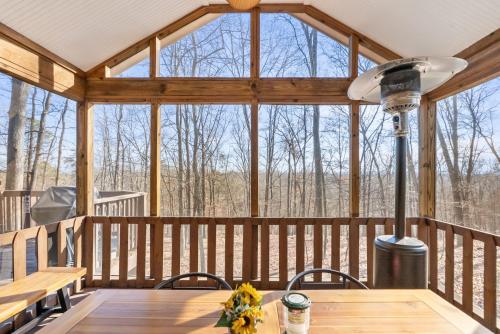 een grote afgeschermde veranda met een houten tafel en stoelen bij 3 Fireplaces Hot Tub Fire Pit Deck Pool Access in Hedgesville
