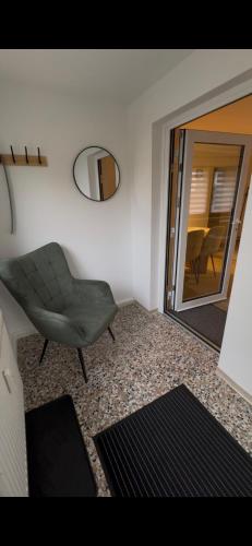 a living room with a green chair and a mirror at Ferienwohnung Krautfassblick in Ortenberg