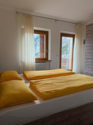 two beds in a bedroom with yellow sheets at Rifugio Capanna Bill in Rocca Pietore