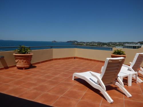 a patio with white chairs and a view of the water at Villa Mar Colina in Yeppoon