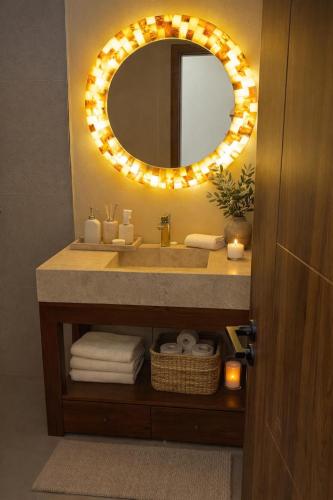 a bathroom with a sink with a mirror and lights at Palma De Maldives in Thoddoo
