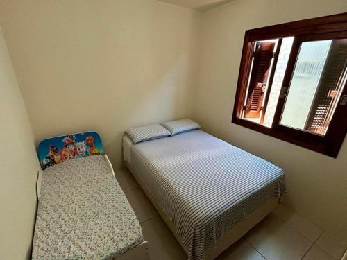 twee eenpersoonsbedden in een kamer met een raam bij Casa aconchegante perto do mar em Imbé in Imbé