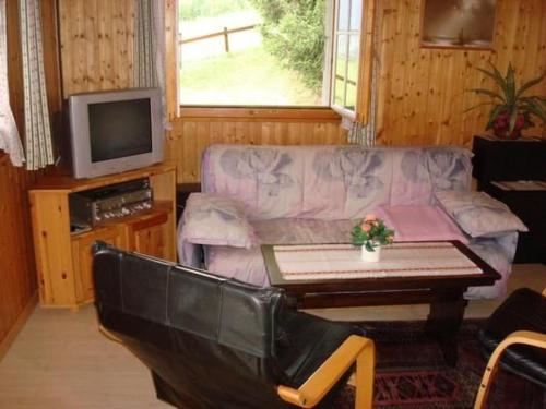 a living room with a couch and a table and a tv at Apartment Chalet Bärli by Interhome in Fiesch