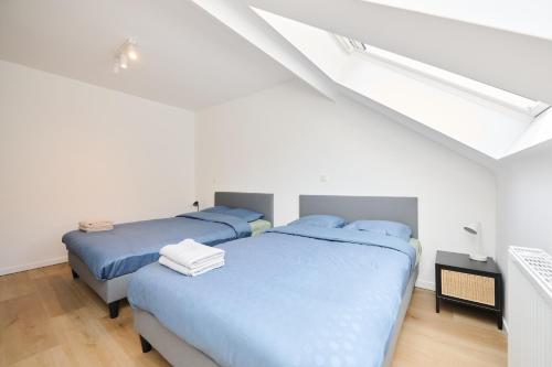 two beds in a white room with blue sheets at Toison d'Or House 4 in Brussels
