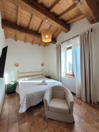 een slaapkamer met een bed, een stoel en een raam bij Il Casale Naturart in Lucciano